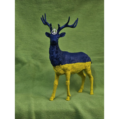 Der Hirsch in Blau und Gelb Stehende Hirschskulptur mit dunkelblauem Oberkörper und Geweih, leuchtend gelben Beinen und einem Friedenssymbol am Kopf.