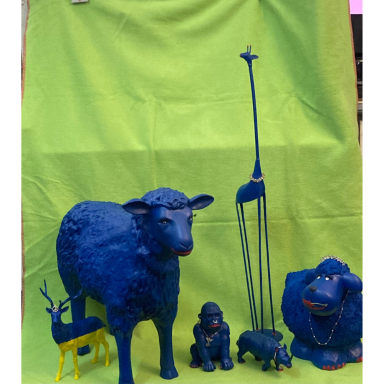 Die blaue Tierfamilie Gruppe verschieden großer blau gestalteter Tierfiguren, darunter eine Giraffe, ein Schaf, ein Affe, ein Nashorn und ein Hirsch, vor grünem S